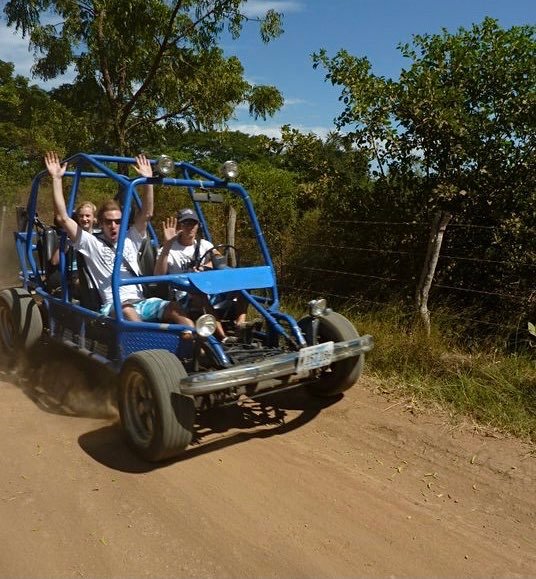 Riding on a dirt road. Passenger has their hands in the air like on a roller coaster.