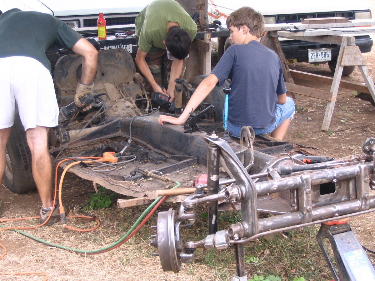 People using mechanic shop cutting tools on a VW beetle chassis.