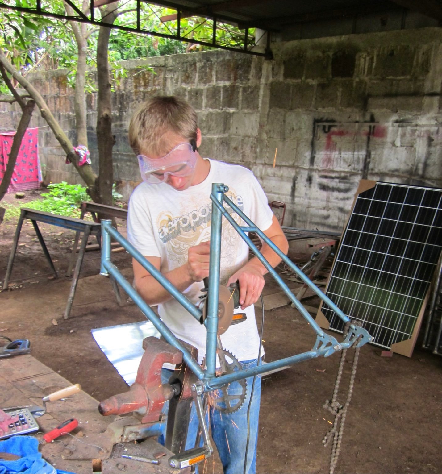 Using a grinding disc to cut up an old bike frame in a rustic shop